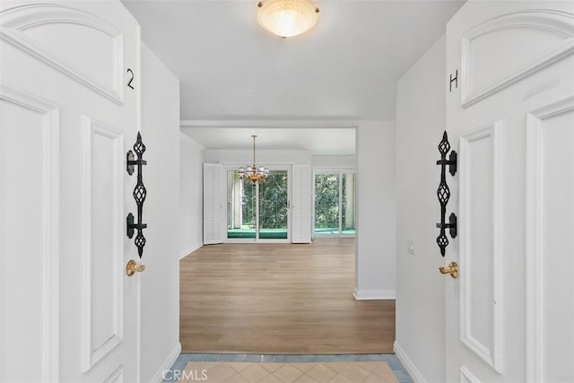 tiled foyer entrance featuring an inviting chandelier and baseboards