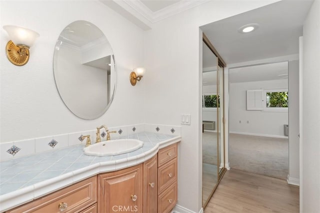 bathroom featuring vanity, wood finished floors, baseboards, and ornamental molding