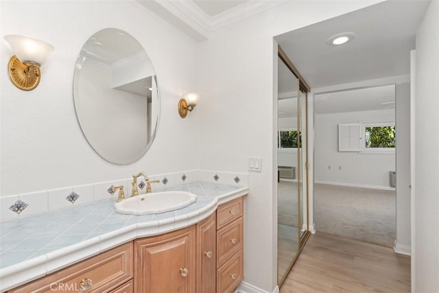 bathroom featuring crown molding, vanity, wood finished floors, and baseboards