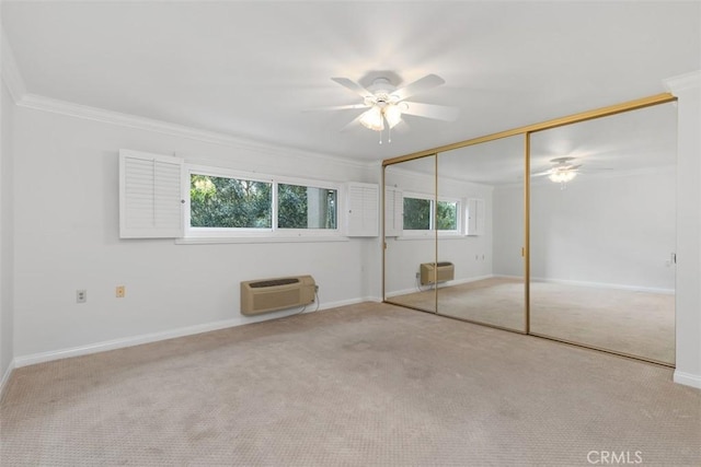 unfurnished bedroom featuring carpet flooring, a wall mounted air conditioner, baseboards, and ornamental molding