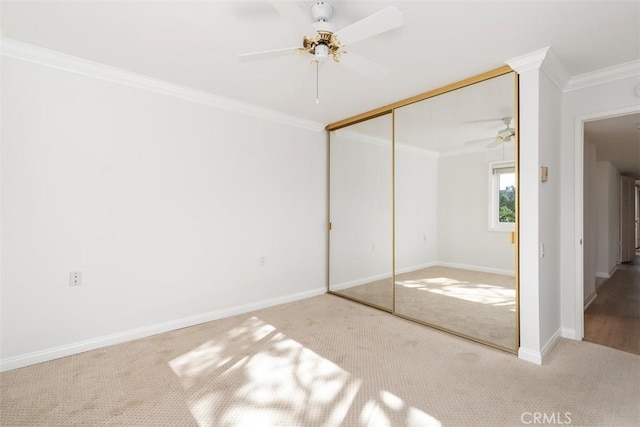 unfurnished bedroom with a closet, baseboards, crown molding, and carpet