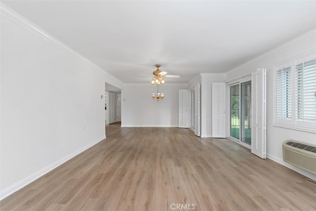 unfurnished living room with a wall mounted air conditioner, baseboards, light wood-style floors, and crown molding