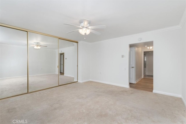 unfurnished bedroom with crown molding, baseboards, carpet floors, a closet, and a ceiling fan