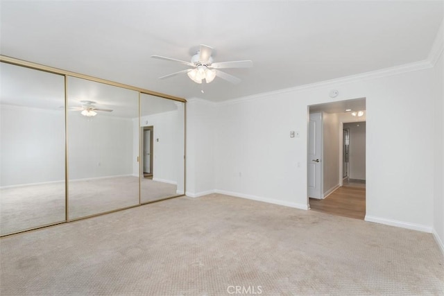 unfurnished bedroom with baseboards, crown molding, a closet, and carpet