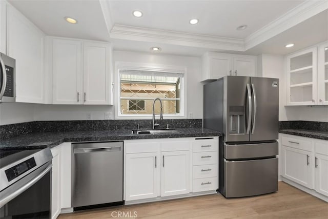 kitchen with appliances with stainless steel finishes, a raised ceiling, ornamental molding, and a sink