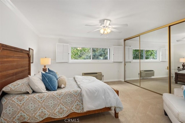 bedroom with crown molding, carpet floors, baseboards, a closet, and an AC wall unit