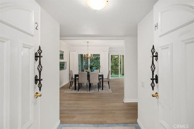 entrance foyer featuring baseboards, an inviting chandelier, and light wood-style flooring