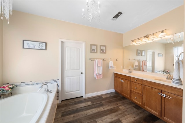 bathroom featuring wood finished floors, visible vents, an inviting chandelier, double vanity, and a garden tub