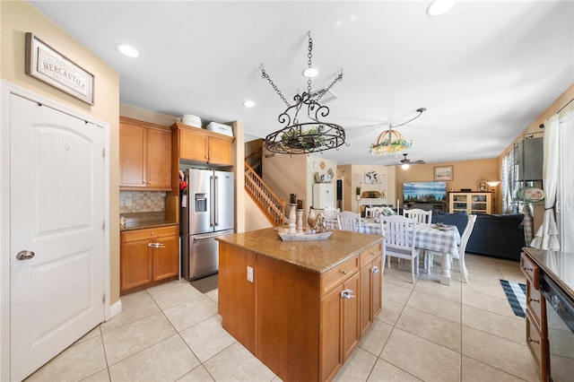 kitchen with stainless steel refrigerator with ice dispenser, open floor plan, a center island, light tile patterned floors, and dishwasher