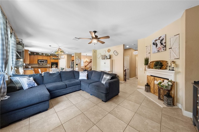 living room with light tile patterned floors, visible vents, baseboards, and a ceiling fan