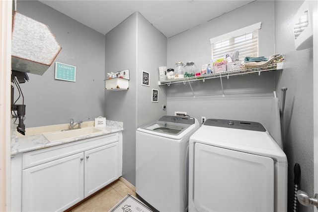 laundry area with cabinet space, washer and dryer, light tile patterned flooring, and a sink