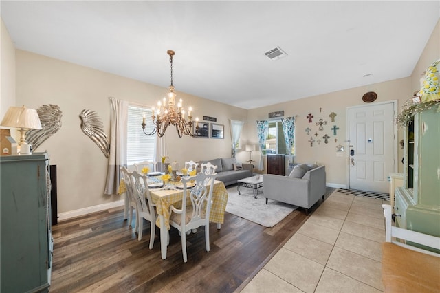 dining room with visible vents, wood finished floors, baseboards, and a chandelier