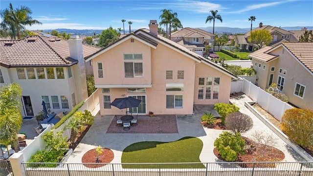 back of property with stucco siding, a fenced backyard, and a chimney