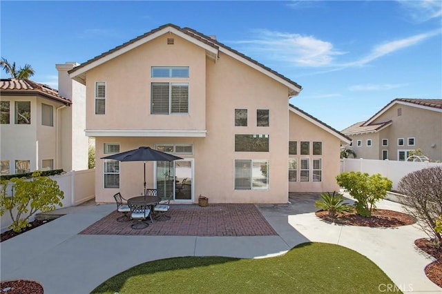 back of property with a tiled roof, a patio area, a fenced backyard, and stucco siding