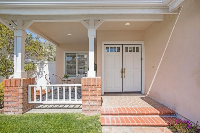 property entrance with covered porch and stucco siding