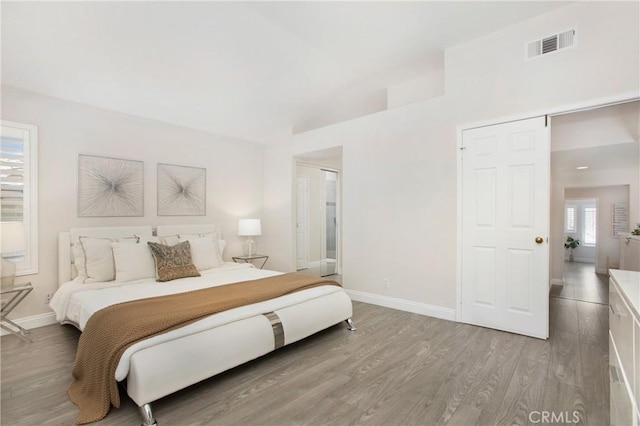 bedroom with visible vents, baseboards, and wood finished floors