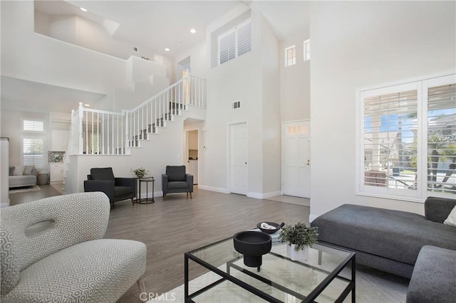 living room with visible vents, wood finished floors, recessed lighting, baseboards, and stairs