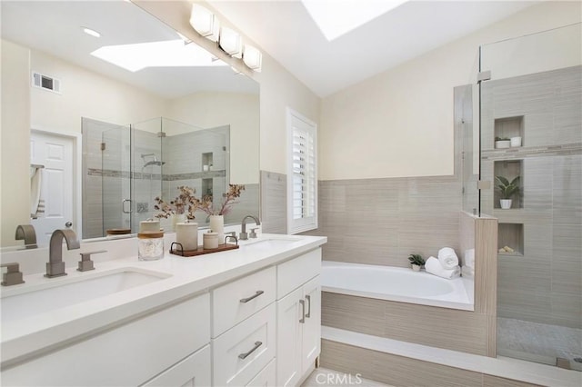 bathroom with double vanity, a shower stall, a skylight, and a sink