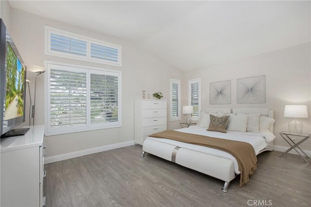 bedroom with baseboards, light wood-type flooring, and lofted ceiling