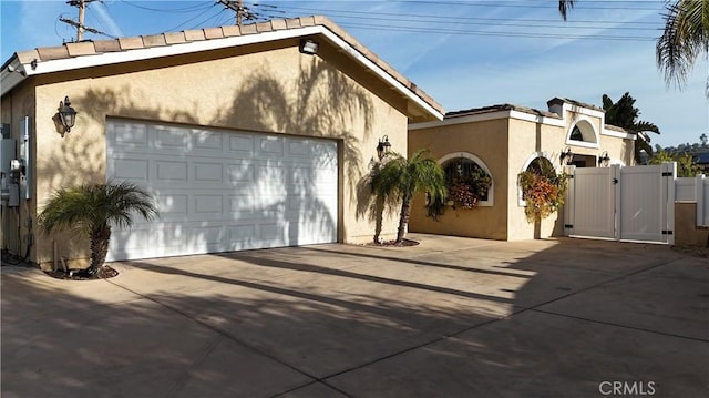 view of front of house featuring stucco siding, a garage, and a gate