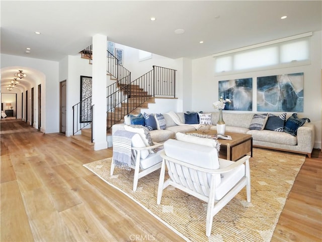 living area featuring recessed lighting, stairway, arched walkways, and light wood finished floors