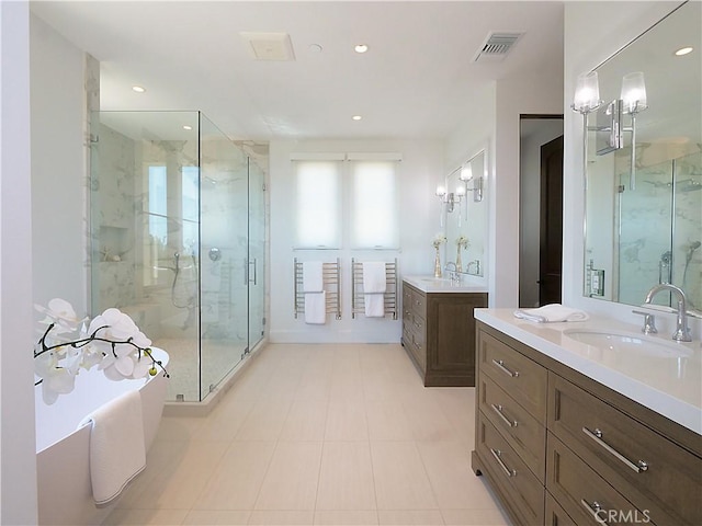 full bathroom with visible vents, two vanities, a sink, a shower stall, and a soaking tub