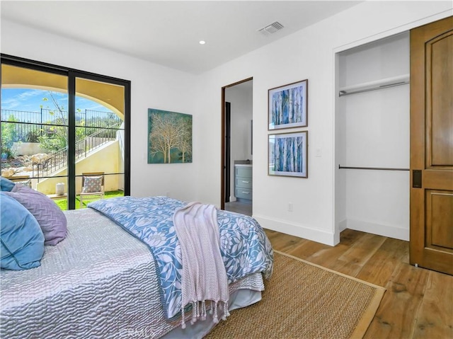 bedroom featuring wood finished floors, visible vents, baseboards, recessed lighting, and connected bathroom