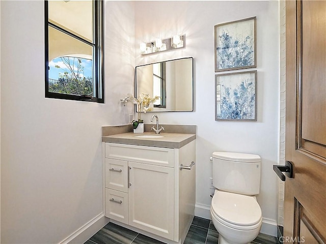 half bathroom featuring baseboards, toilet, and vanity