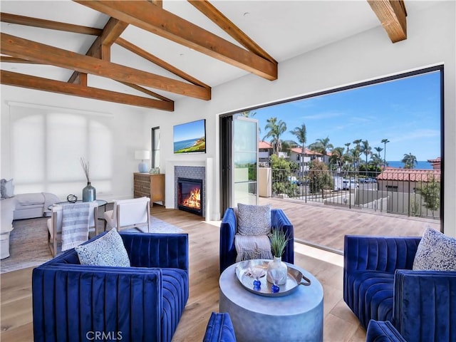 interior space featuring a glass covered fireplace, vaulted ceiling with beams, and wood finished floors