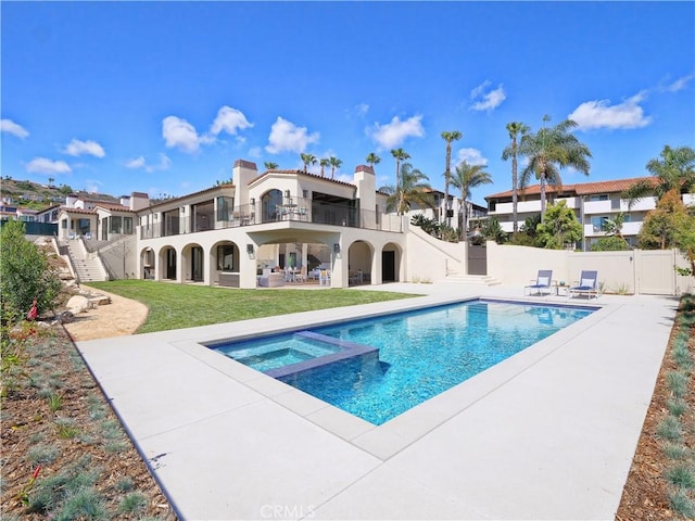 view of swimming pool with a lawn, a pool with connected hot tub, a patio, and fence