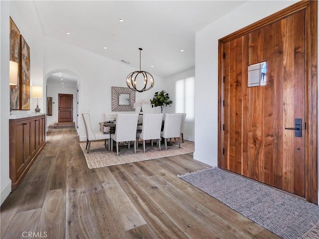 foyer with arched walkways, a notable chandelier, recessed lighting, and hardwood / wood-style flooring