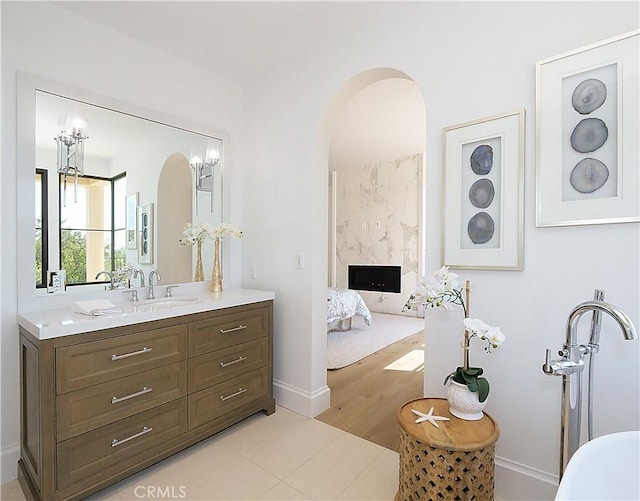 ensuite bathroom featuring connected bathroom, vanity, wood finished floors, and a fireplace