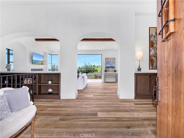 foyer entrance featuring arched walkways, baseboards, and wood finished floors