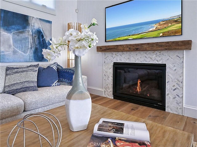 living room featuring a tile fireplace, baseboards, and wood finished floors