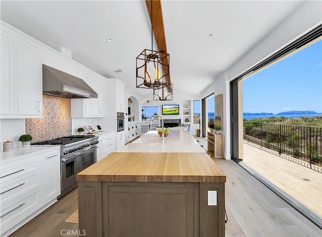 kitchen with open floor plan, appliances with stainless steel finishes, wood counters, and exhaust hood