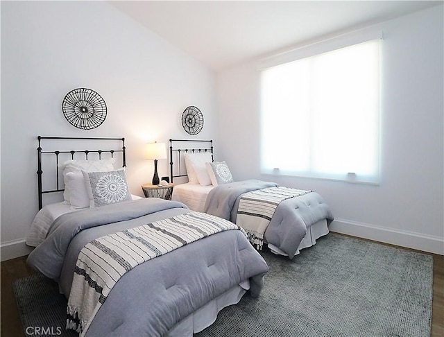 bedroom with baseboards, lofted ceiling, and wood finished floors