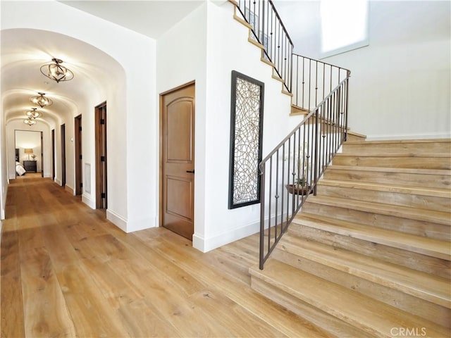 interior space featuring a high ceiling, wood finished floors, arched walkways, and baseboards