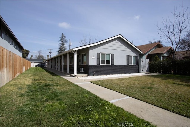 view of front of house with brick siding, a front yard, and fence