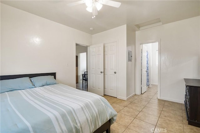 bedroom with light tile patterned flooring, ceiling fan, attic access, and baseboards