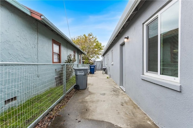 view of side of property featuring a patio, fence, and stucco siding