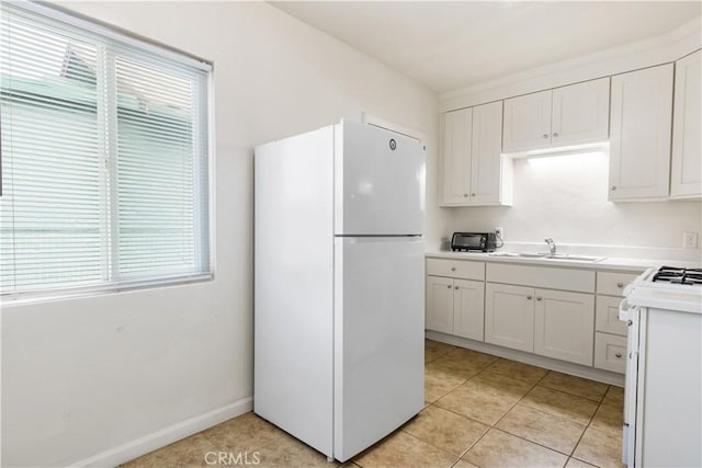 kitchen featuring a sink, white appliances, white cabinets, light countertops, and light tile patterned floors