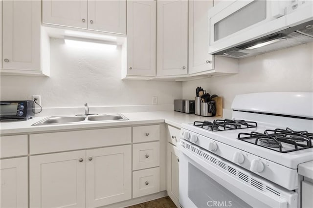 kitchen featuring white cabinets, white appliances, light countertops, and a sink