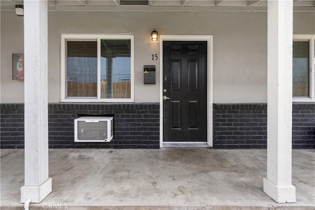 property entrance featuring brick siding, a patio area, and stucco siding