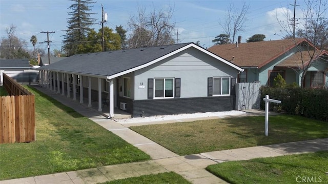 view of front facade with a shingled roof, a front lawn, fence, and stucco siding