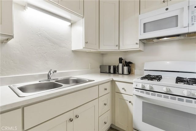 kitchen featuring a sink, white appliances, a textured wall, and light countertops