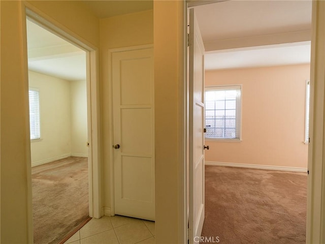 hall featuring light tile patterned floors, light colored carpet, and baseboards