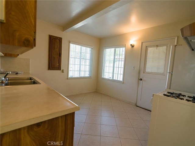 kitchen featuring beamed ceiling, a sink, freestanding refrigerator, light countertops, and light tile patterned floors