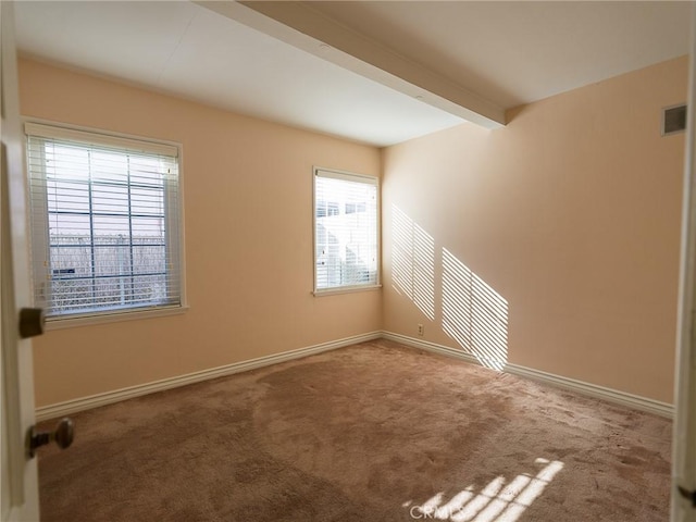 empty room with beamed ceiling, baseboards, carpet, and visible vents