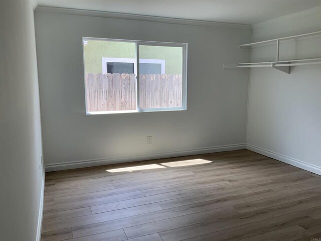 empty room with crown molding, baseboards, and wood finished floors