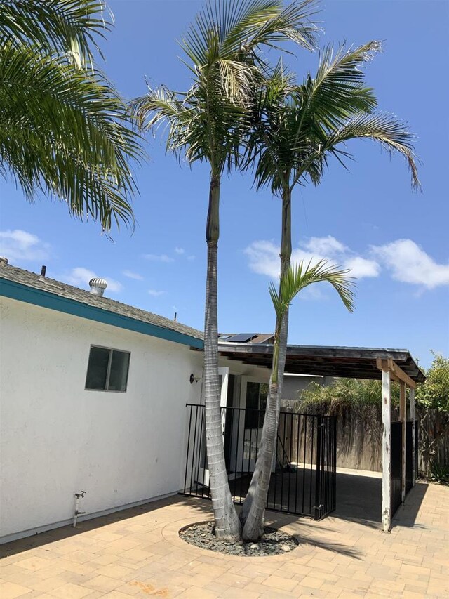 exterior space featuring stucco siding, fence, and solar panels